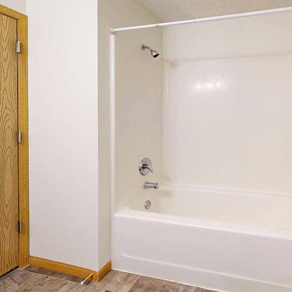 Thumbnail 19 of 29 A white combo shower and tub with a metal towel rack on the right