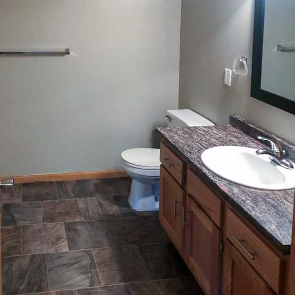 Thumbnail 6 of 6 A bathroom with a granite vanity sink, and framed mirror with overhead lighting.