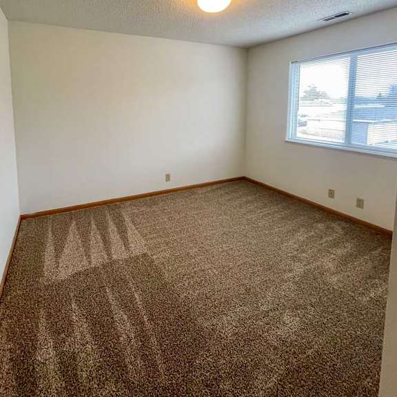 Thumbnail 5 of 10 A bedroom with a carpeted floor and a large window.