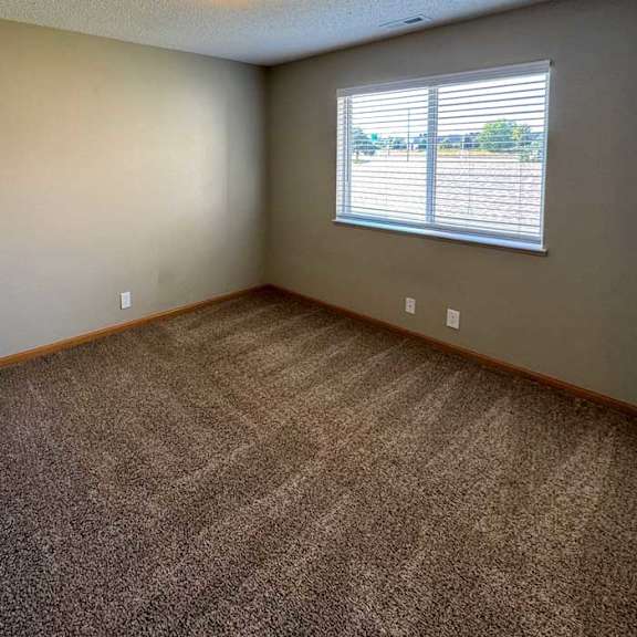 Thumbnail 10 of 10 A bedroom with a carpeted floor and a wide window with blinds.
