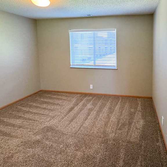 Thumbnail 8 of 10 A bedroom with a carpeted floor and a window with blinds.