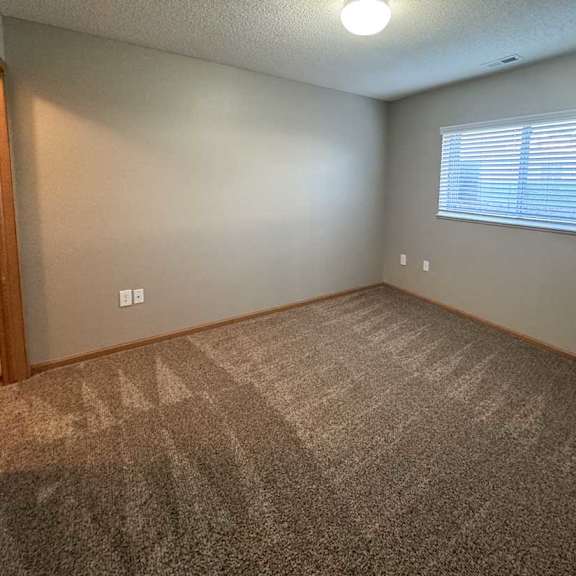 Thumbnail 5 of 9 A bedroom with a carpeted floor and a window with blinds.