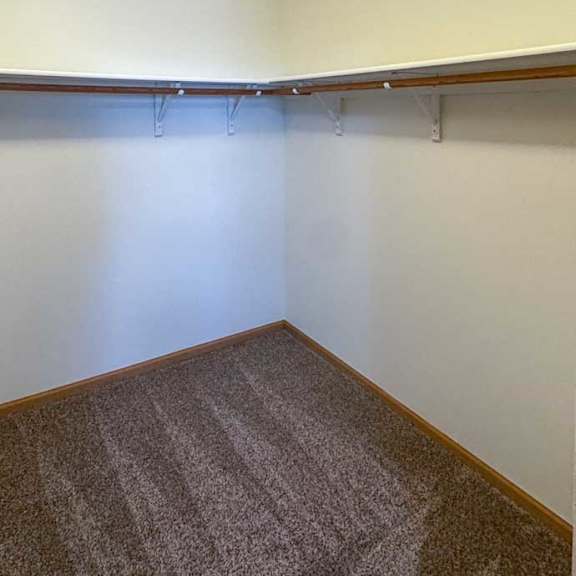 Thumbnail 6 of 9 A walk-in closet with built in shelving and hanging space.