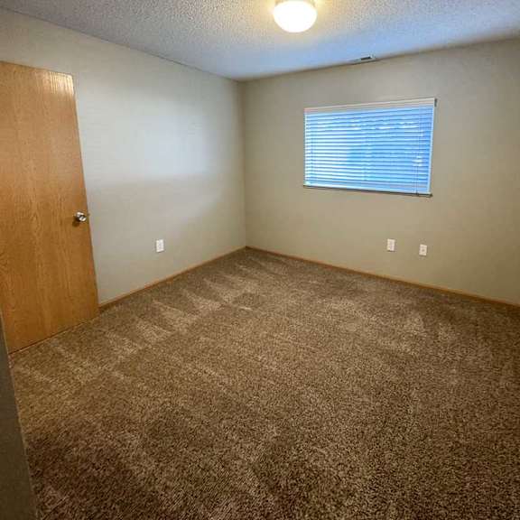 Thumbnail 8 of 9 A bedroom with a carpeted floor and a window with blinds.