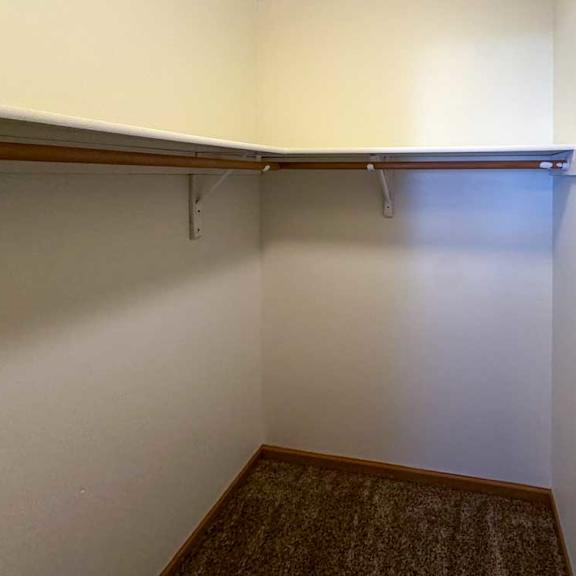 Thumbnail 9 of 9 A walk-in closet with a built in overhead shelf and hanging space.