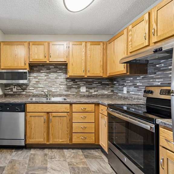 Thumbnail 12 of 20 A kitchen with wooden cabinets and a stone backsplash.