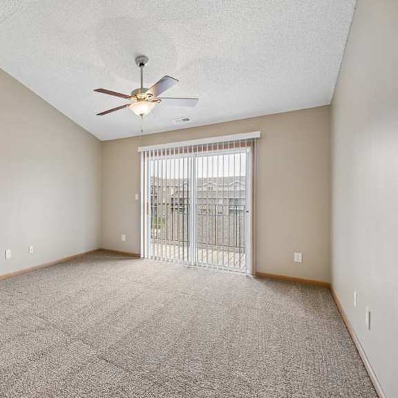Thumbnail 3 of 20 A spacious room with a ceiling fan and a sliding glass door leading to a balcony.