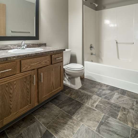 Thumbnail 11 of 14 a bathroom with wooden cabinets, a granite vanity sink, a mirror, and a combination shower and tub