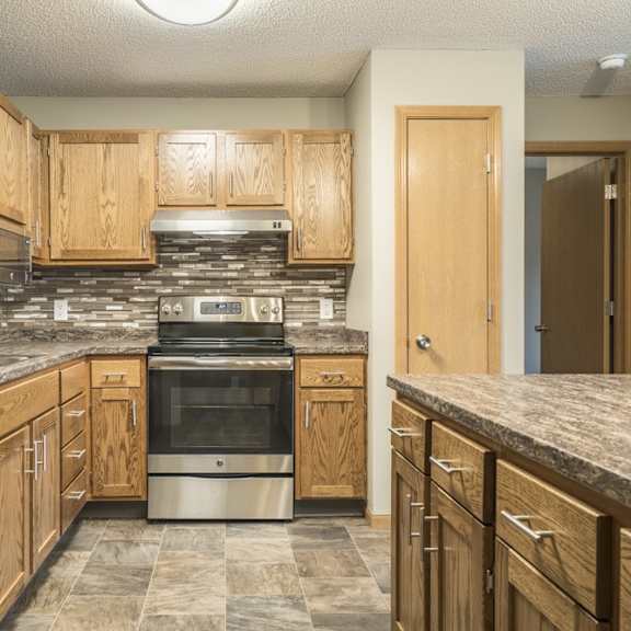 Thumbnail 5 of 14 an updated kitchen featuring wooden cabinets, granite countertops, a tile backsplash, stainless steel appliances, and a kitchen island