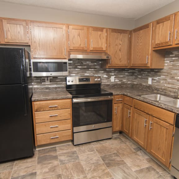 Thumbnail 3 of 10 a kitchen with wooden cabinets and a black refrigerator