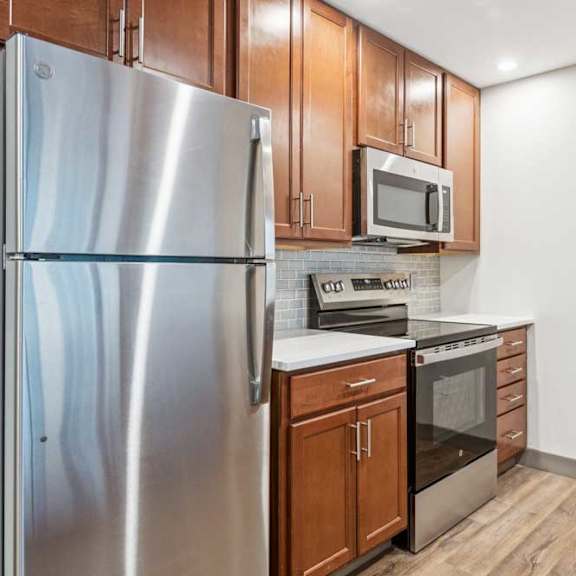 Thumbnail 3 of 19 A modern kitchen with wooden cabinets, granite countertops, a tile backsplash, and stainless steel appliances.