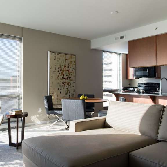 Thumbnail 5 of 10 A living room with a grey sofa, a chair, a table, and huge windows