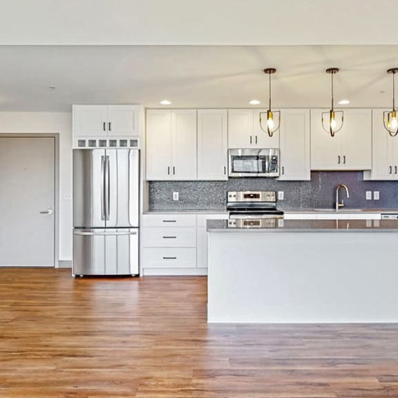 Thumbnail 5 of 22 Large kitchen with island, white cabinets, stainless appliances, and warm tan floors