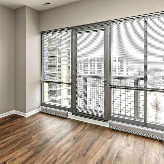 Thumbnail 6 of 9 floor to ceiling windows in a living room with warm brown wood floors