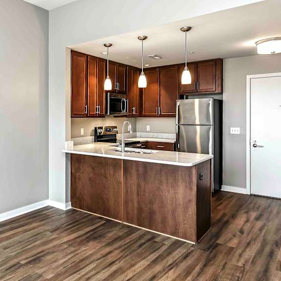 Thumbnail 7 of 9 U-shaped kitchen with warm dark brown cabinets and pendant lighting
