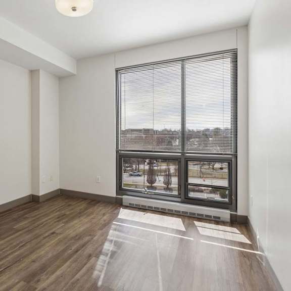 Thumbnail 3 of 11 A room with a large window and wooden flooring.