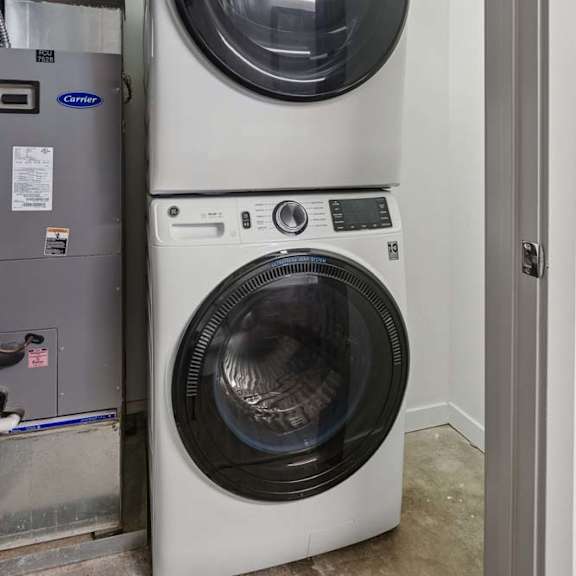 Thumbnail 8 of 11 A white front load washing machine is stacked on top of another in a room.