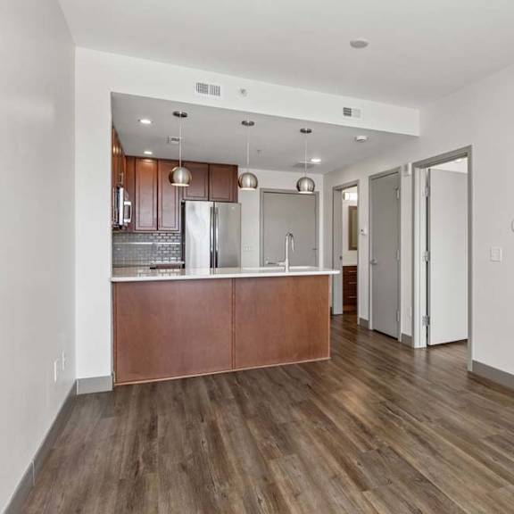 Thumbnail 6 of 11 A kitchen with a wooden floor and white walls.