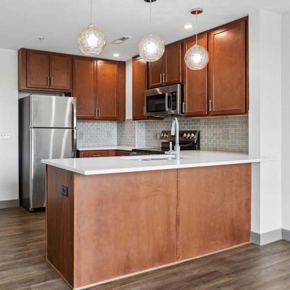 Thumbnail 32 of 35 A kitchen with wooden cabinets and a white countertop.