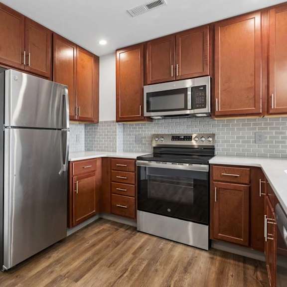 Thumbnail 25 of 35 A kitchen with wooden cabinets and stainless steel appliances.