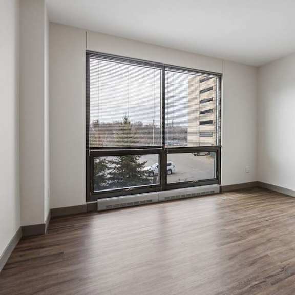 Thumbnail 26 of 35 An empty apartment living room with vinyl wood flooring, a large floor to ceiling window, and a city view,.