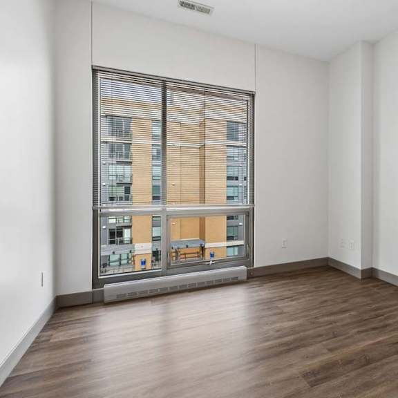 Thumbnail 22 of 35 A room with a large window overlooking a building.
