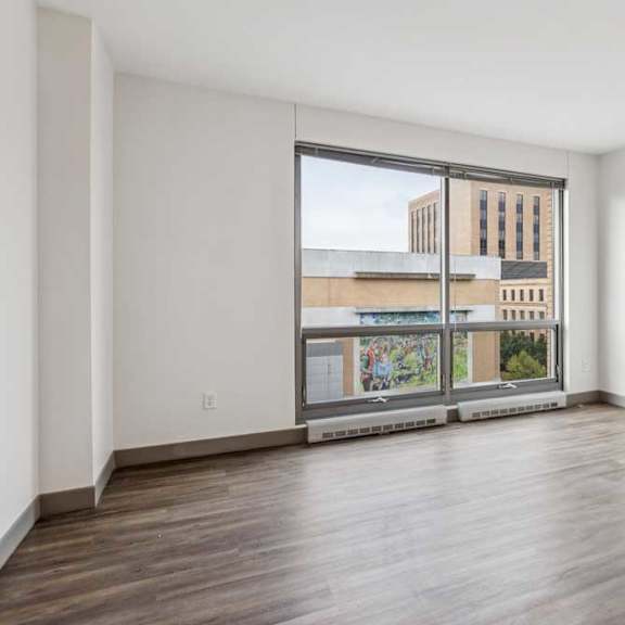 Thumbnail 10 of 16 A living room with hardwood-style flooring and a floor-to-ceiling window.