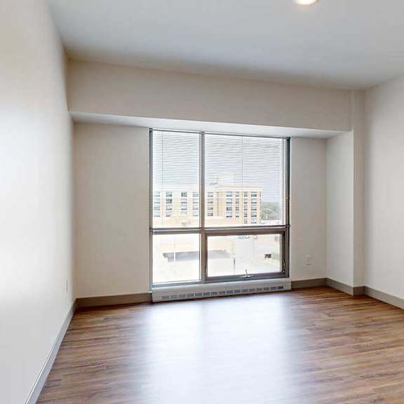 Thumbnail 13 of 24 A bedroom with hardwood-style flooring and a floor-to-ceiling window.