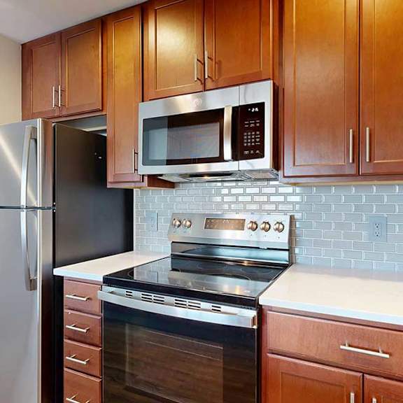 Thumbnail 5 of 24 A modern kitchen with a stainless steel range, refrigerator, and microwave.