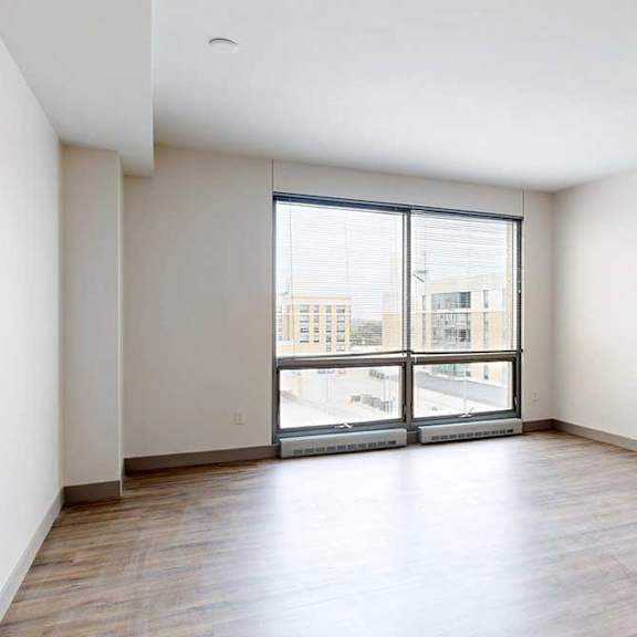 Thumbnail 9 of 24 A living room with hardwood-style flooring and a floor-to-ceiling window.