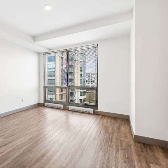Thumbnail 15 of 20 A room with wooden flooring and a large window with a view of a cityscape.