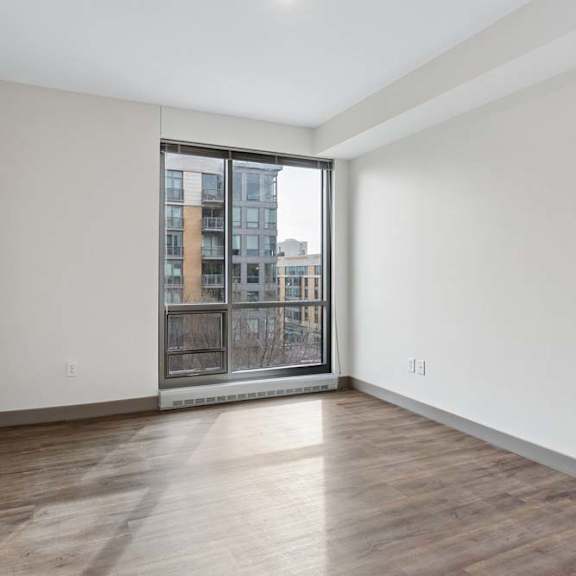 Thumbnail 13 of 19 A room with a large window and wooden flooring.