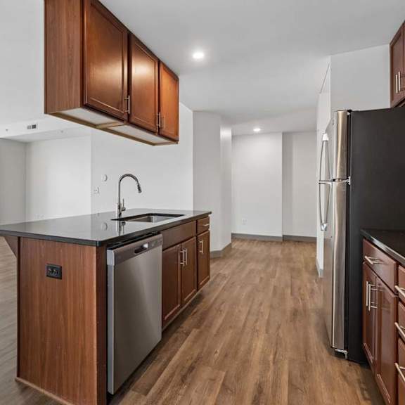 Thumbnail 6 of 19 A kitchen with wooden cabinets and a black fridge.