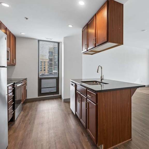 Thumbnail 12 of 19 A kitchen with wooden cabinets and a black countertop.
