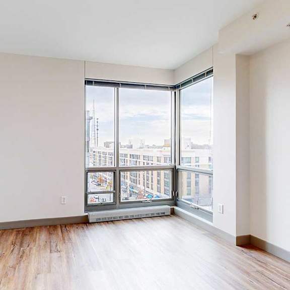 Thumbnail 21 of 24 a bedroom with a corner floor-to-ceiling window and hardwood floors