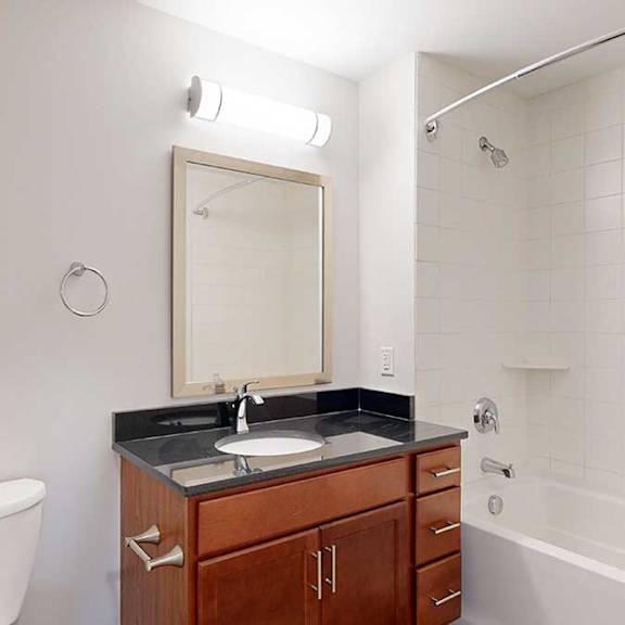 Thumbnail 23 of 24 A bathroom with a toilet, sink, mirror, and a bathtub.