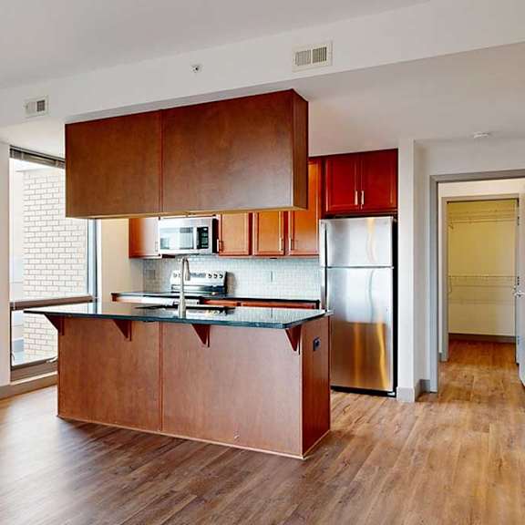 Thumbnail 8 of 24 a kitchen island featuring warm-brown cabinets and stainless steel appliances