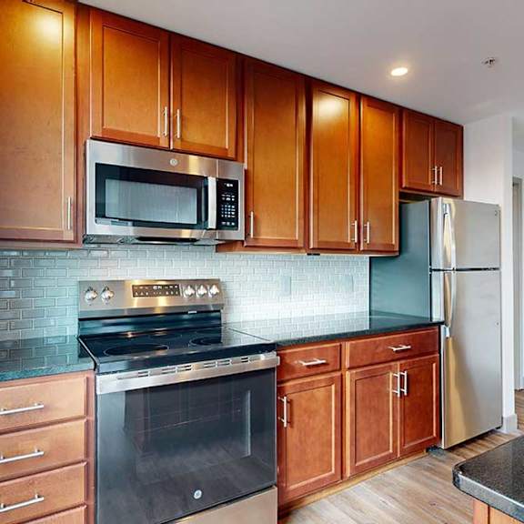 Thumbnail 9 of 24 a modern kitchen with brown wooden cabinets, stainless steel appliances, black granite countertops, and a tile backsplash