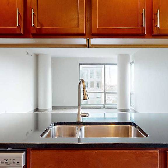 Thumbnail 11 of 24 a kitchen sink in an island with a black granite countertop and brown wooden cabinets