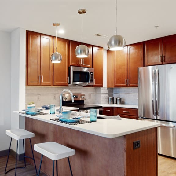 Thumbnail 8 of 14 Kitchen with peninsula countertop, tile backsplash, and modern appliances in a 1 bedroom floor plan at Midtown Crossing Apartments Omaha