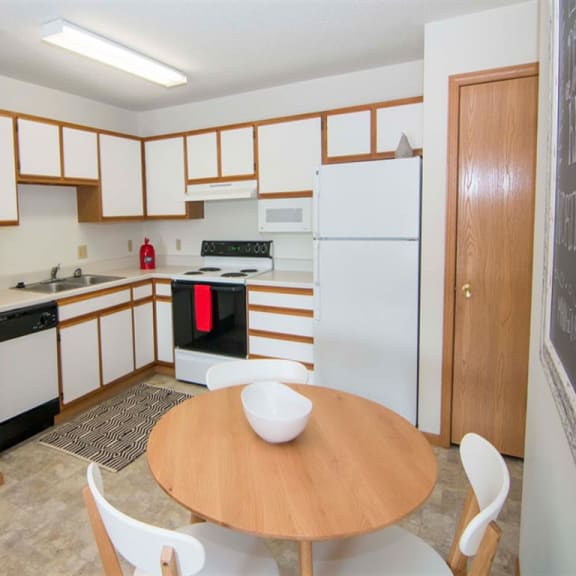 Thumbnail 3 of 5 L-shaped kitchen with white cabinets and small dining area
