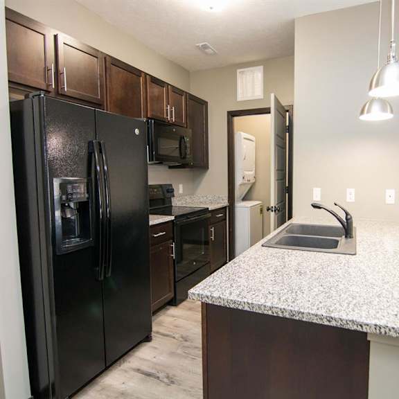 Thumbnail 2 of 9 Gallery style kitchen with dark brown cabinets and black appliances