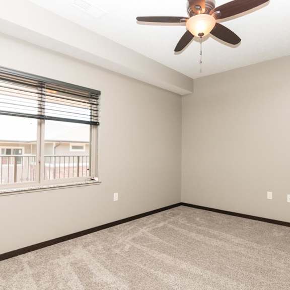 Thumbnail 7 of 9 A room with a ceiling fan and a window with blinds.