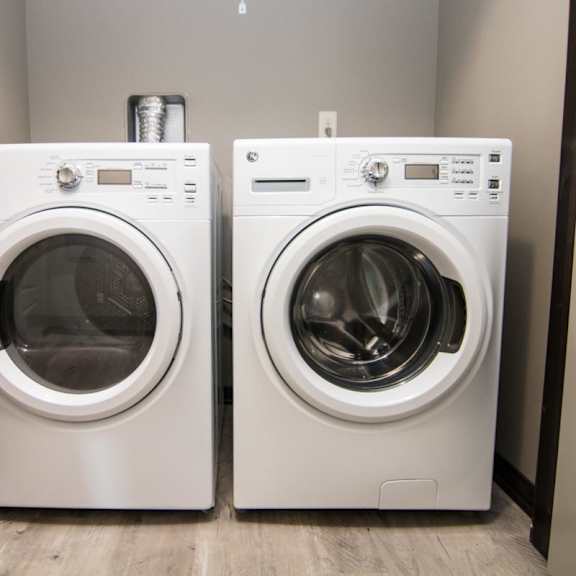 Thumbnail 12 of 13 Two front loading washing machines in a laundry room.