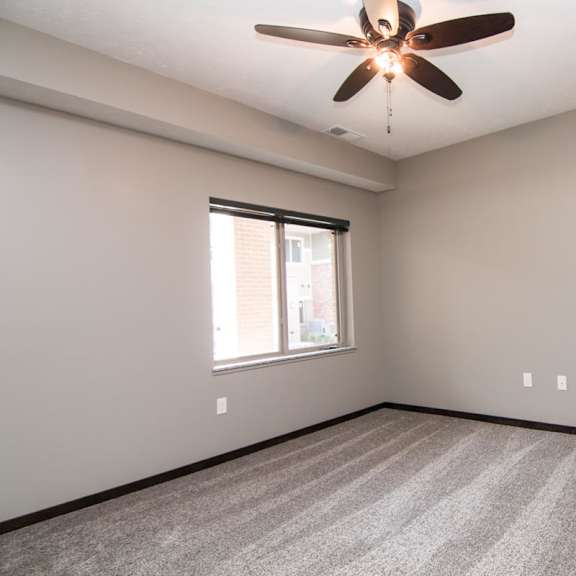Thumbnail 6 of 13 A room with a ceiling fan and carpeted floor.