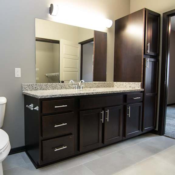 Thumbnail 8 of 13 A bathroom with a white toilet and a marble counter top.