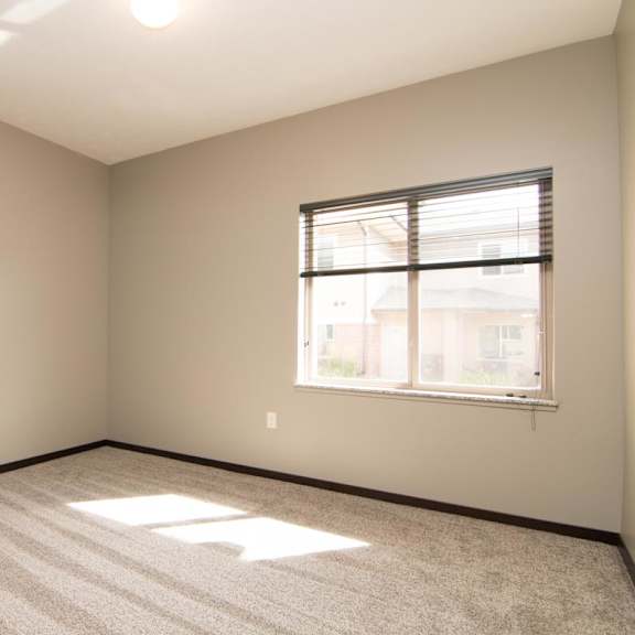 Thumbnail 9 of 13 A room with a carpeted floor and a window with blinds.