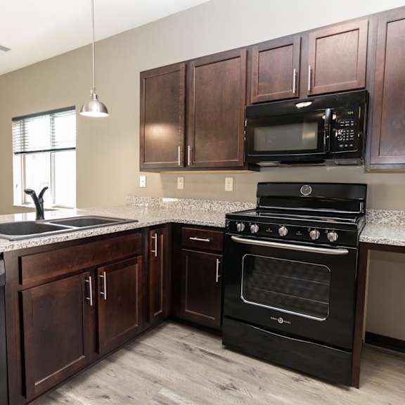 Thumbnail 3 of 13 A kitchen with dark wood cabinets and black appliances.