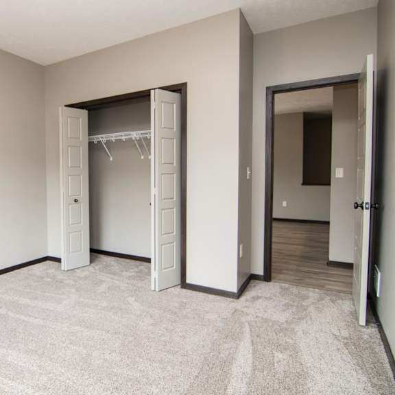 Thumbnail 9 of 14 A room with a carpeted floor and a closet with a door open.