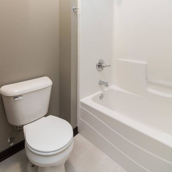 Thumbnail 11 of 14 A white toilet and bathtub in a bathroom.